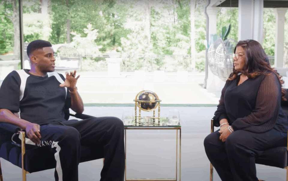 Alicia Lyttle and Nehemiah Davis in a live interview discussing AI automation for entrepreneurs, seated in a modern studio with floor-to-ceiling windows.